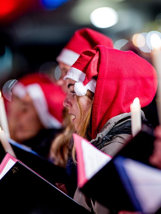 Menschen mit Weihnachtsmützen singen Weihnachtslieder in einem Stadion Menschen mit Weihnachtsmützen singen Weihnachtslieder in einem Stadion