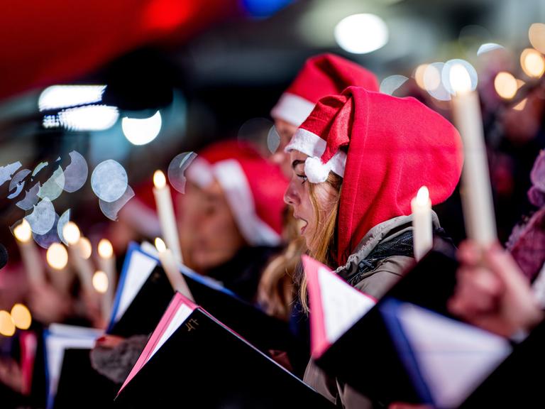 Menschen mit Weihnachtsmützen singen Weihnachtslieder in einem Stadion Menschen mit Weihnachtsmützen singen Weihnachtslieder in einem Stadion