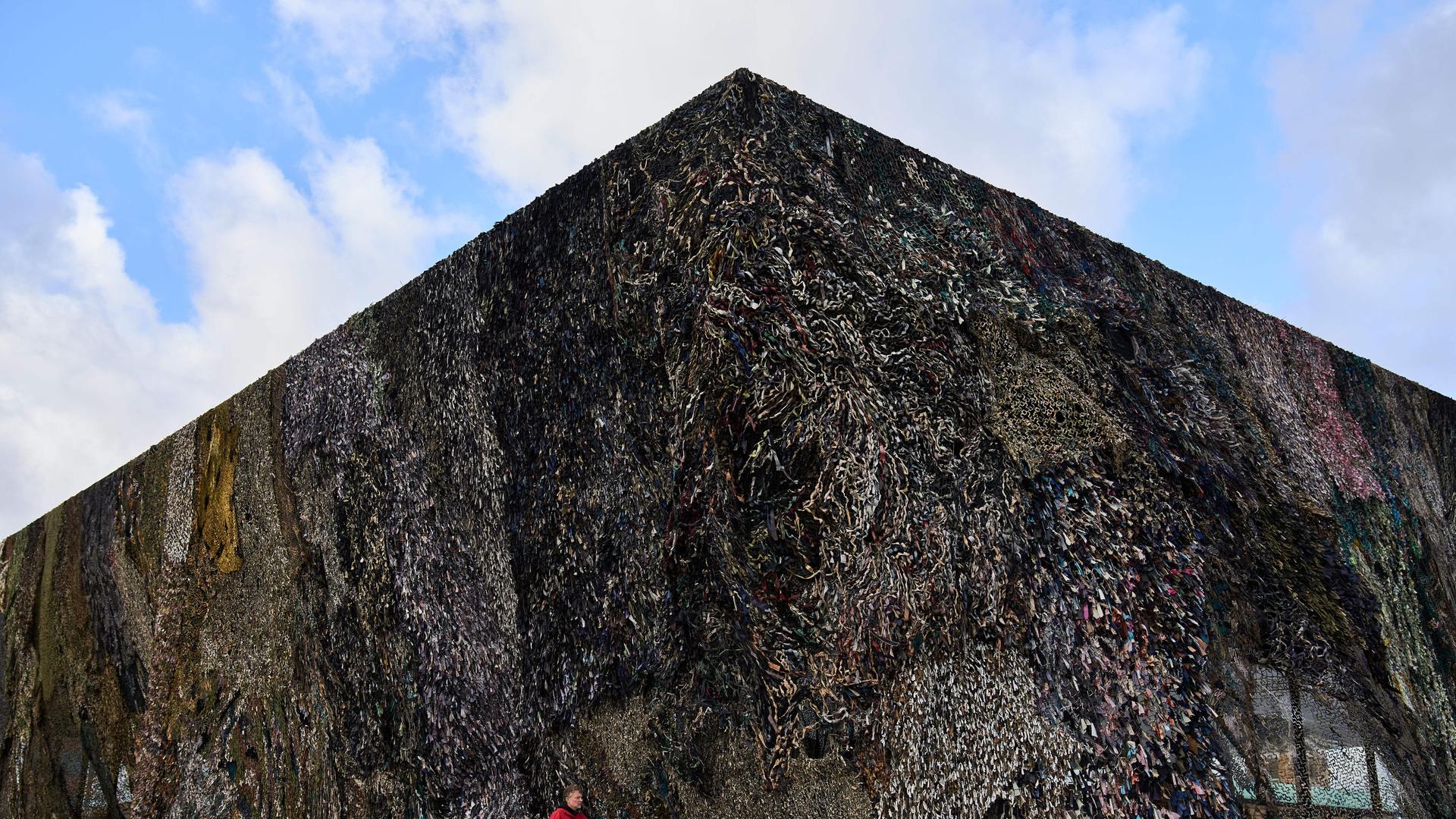 A man walks past an art installation by Fabian Knecht, titled "Laughing Is Suspicious" at the Neue Nationalgalerie in Berlin, Germany, Thursday, Oct. 30, 2025. (AP Photo/Ebrahim Noroozi)