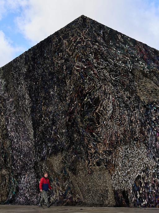 A man walks past an art installation by Fabian Knecht, titled "Laughing Is Suspicious" at the Neue Nationalgalerie in Berlin, Germany, Thursday, Oct. 30, 2025. (AP Photo/Ebrahim Noroozi)