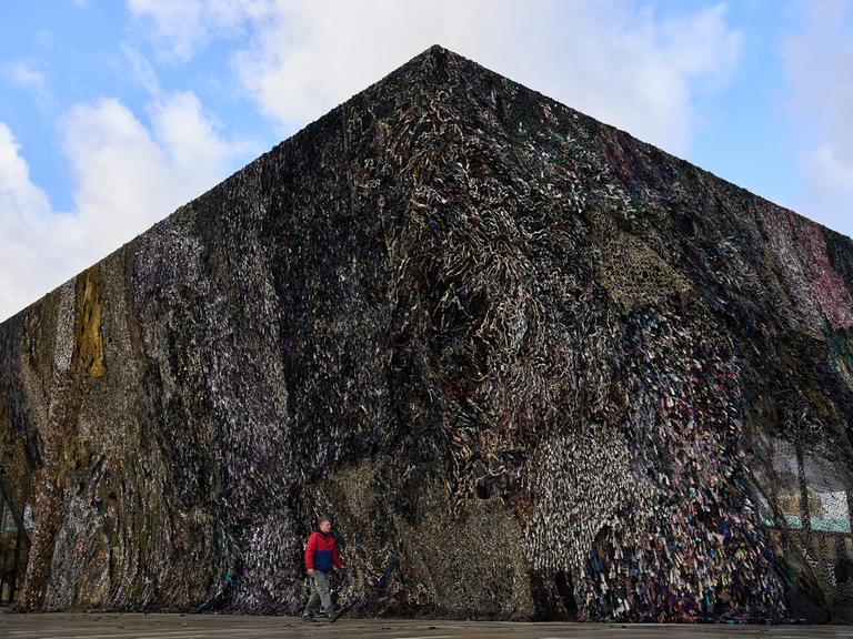 A man walks past an art installation by Fabian Knecht, titled "Laughing Is Suspicious" at the Neue Nationalgalerie in Berlin, Germany, Thursday, Oct. 30, 2025. (AP Photo/Ebrahim Noroozi)