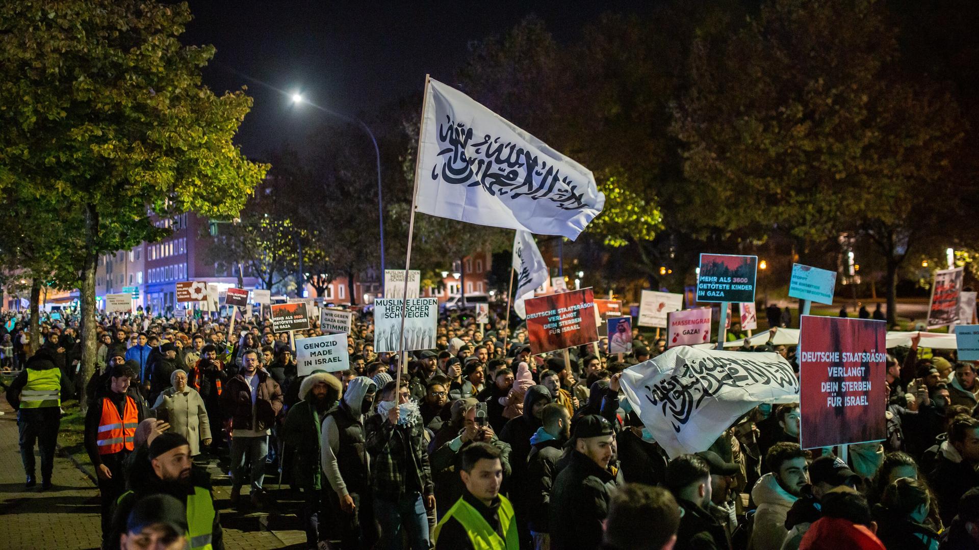 Eine Menschenmenge zieht auf einer pro-palästinensischen Demonstration in der Dunkelheit durch Essen. Die Menschen tragen Transparente und Fahnen. Aufnahme vom 03.11.2023.