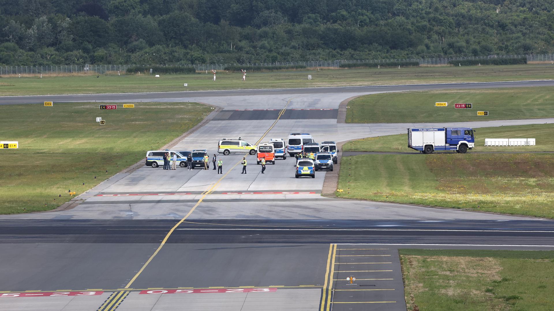 Blick auf das Rollfeld am Flughafen Hamburg: Es sind weit entfernt Einsatzwagen und einzelne Menschen zu sehen. Ansonsten ist das Rollfeld leer.