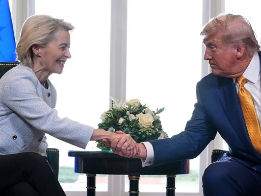 US-Präsident Trump traf die Präsidentin der Europäischen Kommission, von der Leyen, zu Gesprächen in Schottland. Beide schütteln die Hände und lächeln.