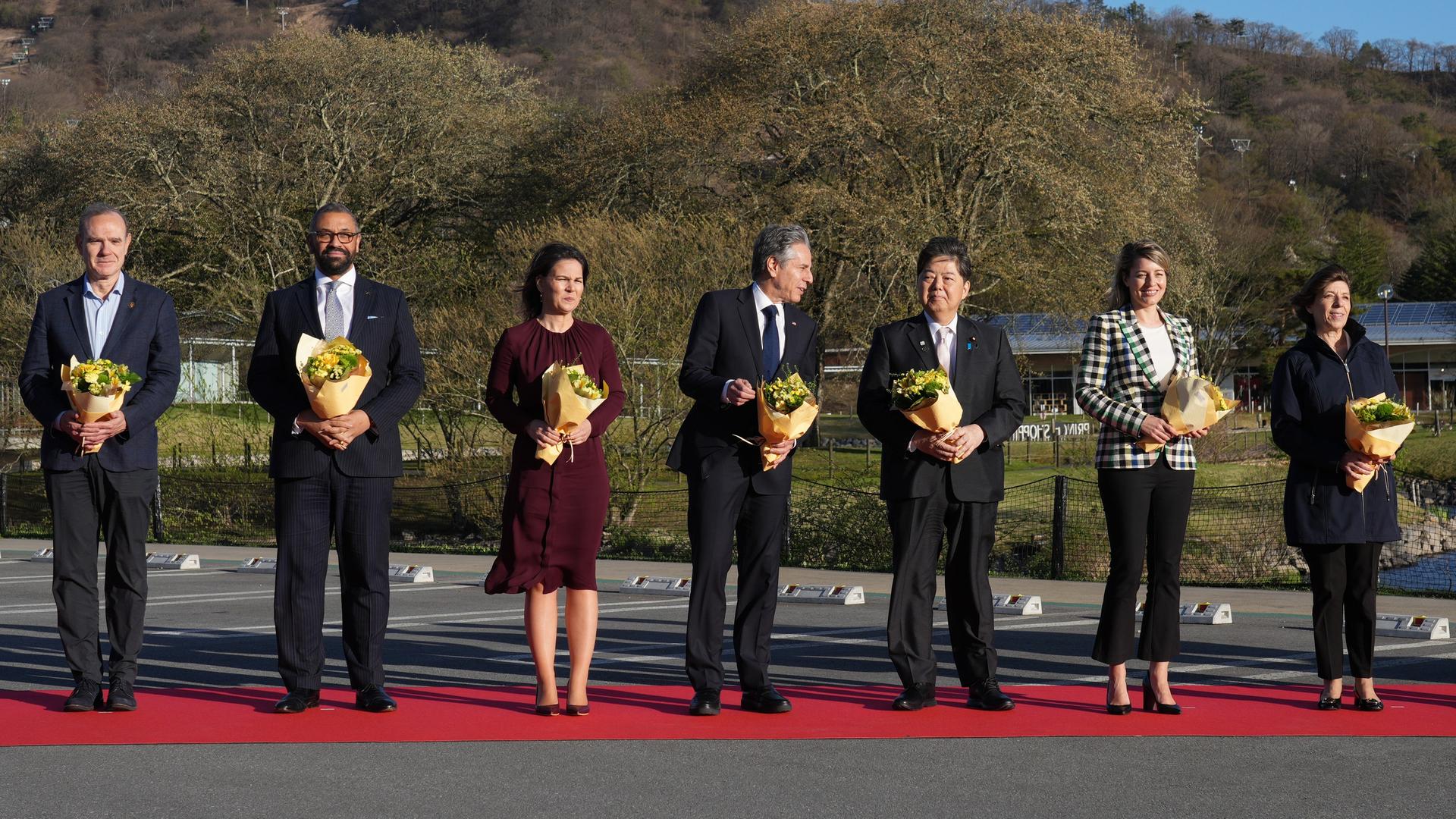 Japan, Karuizawa: Bundesaußenministerin Baerbock steht zwischen Ihren Kollegen von Italien, Großbritannien, den USA, Japan, Kanada und Frankreich beim Abschlusstreffen der G7-Staaten. Alle halten einen Blumenstrauß in der Hand.