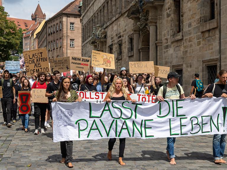 Demonstrationszug in der Innenstadt von Nürnberg gegen die geplante Tötung von Guinea-Pavianen im Tiergarten Nürnberg. An der Spitze der Versammlung tragen mehrere Personen ein grosses Transparent mit der Aufschrift "Lasst die Paviane leben!".
