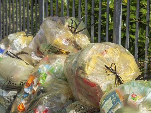 Gelbe Säcke mit Plastikmüll stapeln sich an einer Straße.