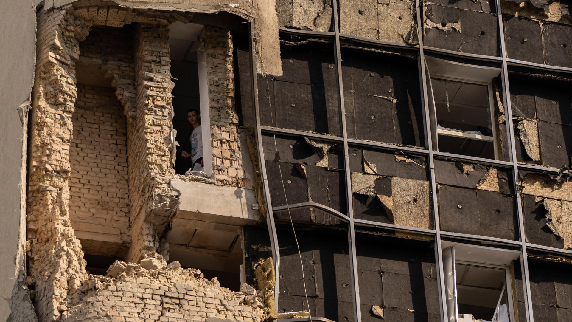 Eine Person schaut aus dem Fenster eines beschädigten Gebäudes in Kiew. Eine Person schaut aus dem Fenster eines beschädigten Gebäudes in Kiew.