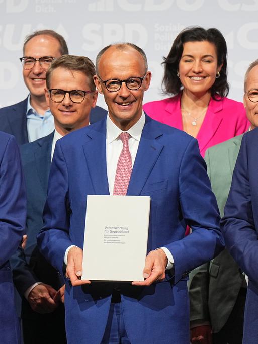 CDU-Vorsitzender und -Kanzlerkandidat Friedrich Merz (M), CSU-Vorsitzender Markus Söder (l) und SPD-Vorsitzender Lars Klingbeil (r) stehen nach der Unterzeichnung des Koalitionsvertrags auf der Bühne.