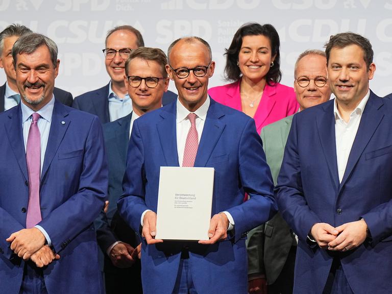 CDU-Vorsitzender und -Kanzlerkandidat Friedrich Merz (M), CSU-Vorsitzender Markus Söder (l) und SPD-Vorsitzender Lars Klingbeil (r) stehen nach der Unterzeichnung des Koalitionsvertrags auf der Bühne.