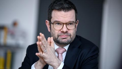 Justizminister Marco Buschmann (FDP) sitzt an einem Tisch und legt die Hände aufeinander.
