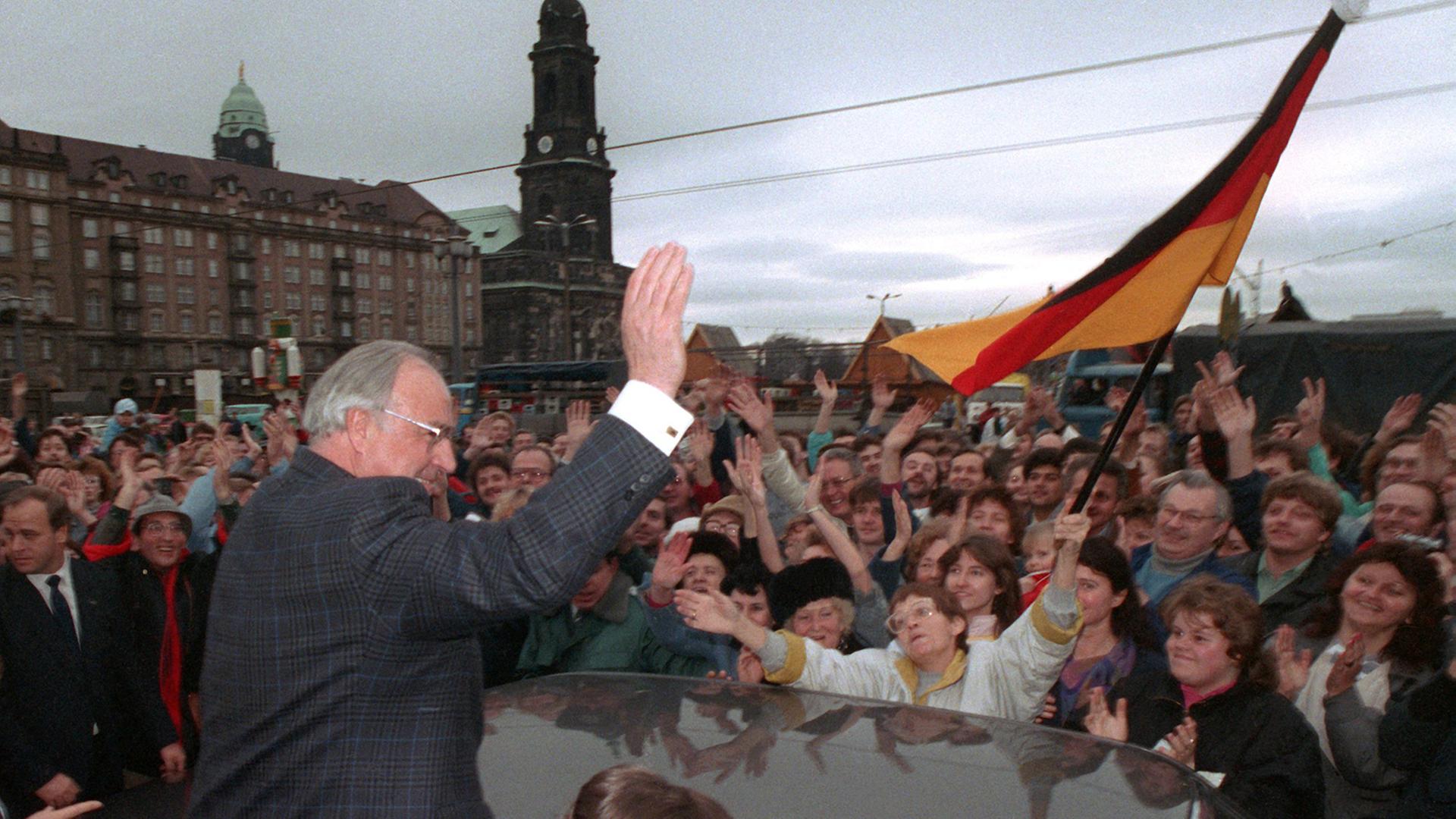 Bundeskanzler Helmut Kohl (CDU) wird am 19. Dezember 1989 anlässlich seines zweitägigen Besuches in der sächsischen Stadt Dresden vor der Kreuzkirche von einer wartenden Menschenmenge stürmisch gefeiert.