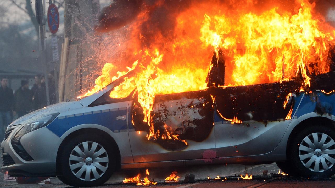 Ein brennendes Polizeiauto am Rande der Proteste