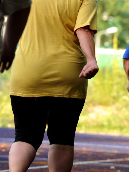 Übergewichtige Frauen und Männern bei Ausdauerübungen auf einem Sportplatz