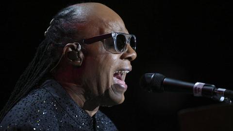 Stevie Wonder im Profil, laut in ein Mikrofon singend