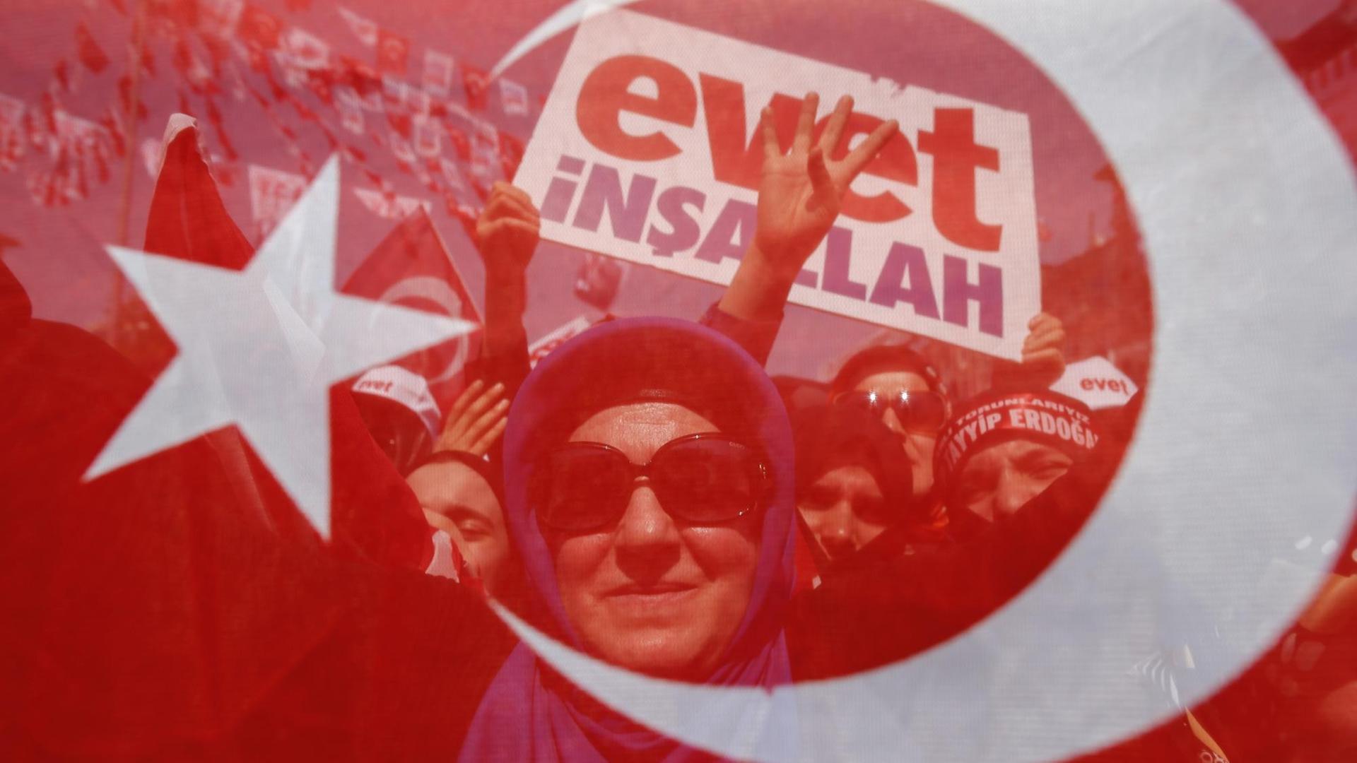 Eine Frauen ist beim Wahlkampfabschluss am 15.04.2017 in Sariyer nahe Istanbul in der Türkei hinter einer türkischen Fahne zu sehen.