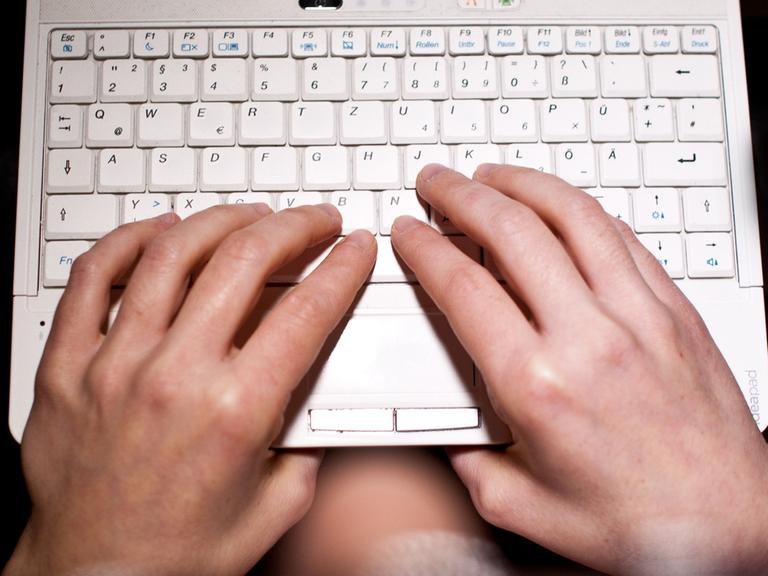 Eine Frau tippt auf ihrem Laptop.