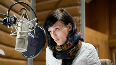 Die Schauspielerin Maria Kwiatkowsky bei einer Hörspielaufnahme im Studio am Mikrofon.