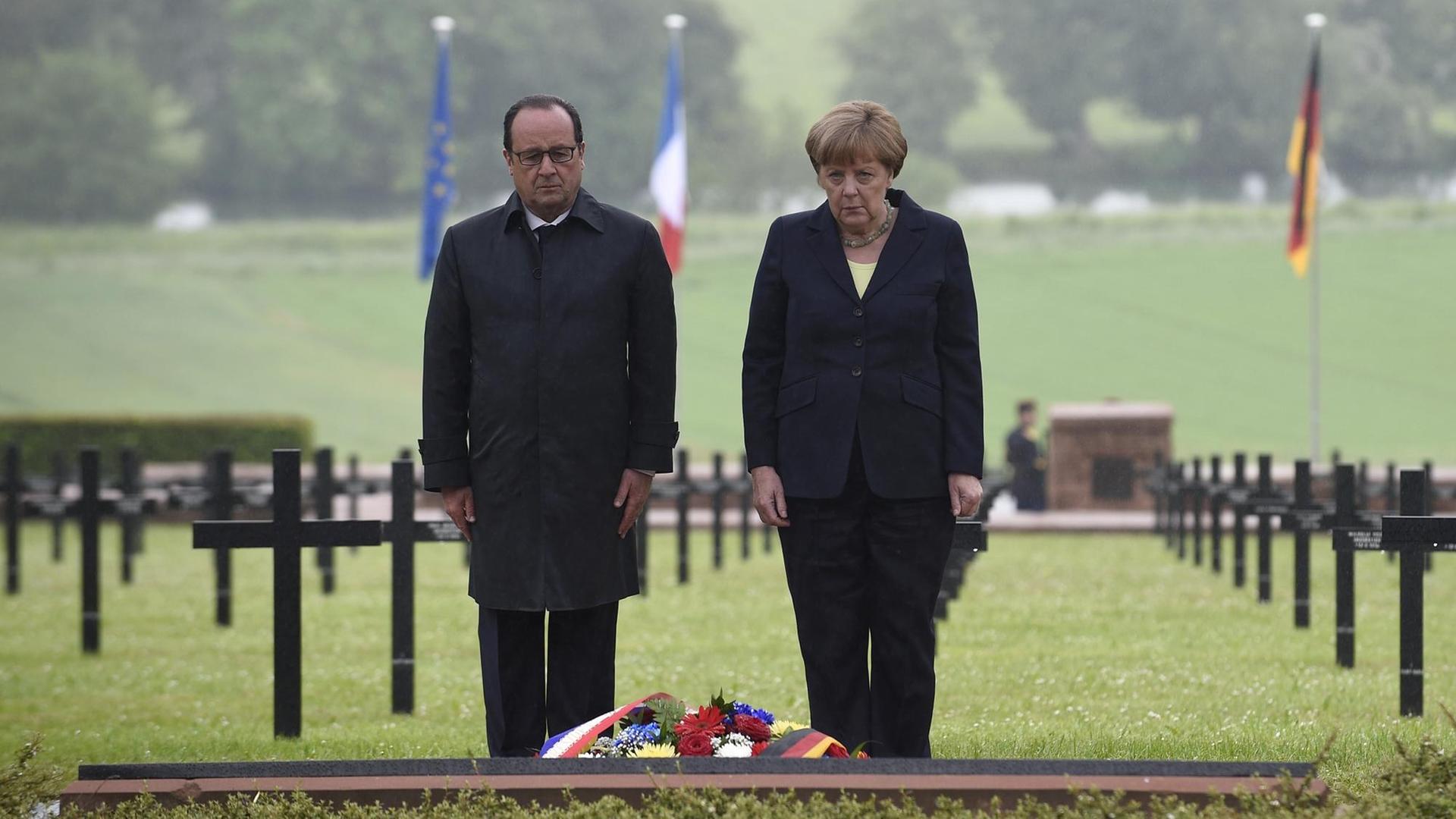 Frankreichs Präsident Francois Hollande und Bundeskanzlerin Angela Merkel stehen vor einem niedergelegten Kranz auf einem deutschen Soldatenfriedhof nördlich von Verdun.