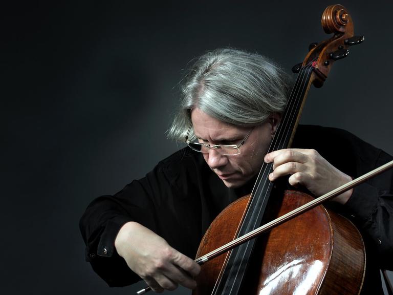 Der Cellist hat sich nah an den Korpus seines Instrumentes gebeugt und streicht intensiv über die Saiten.