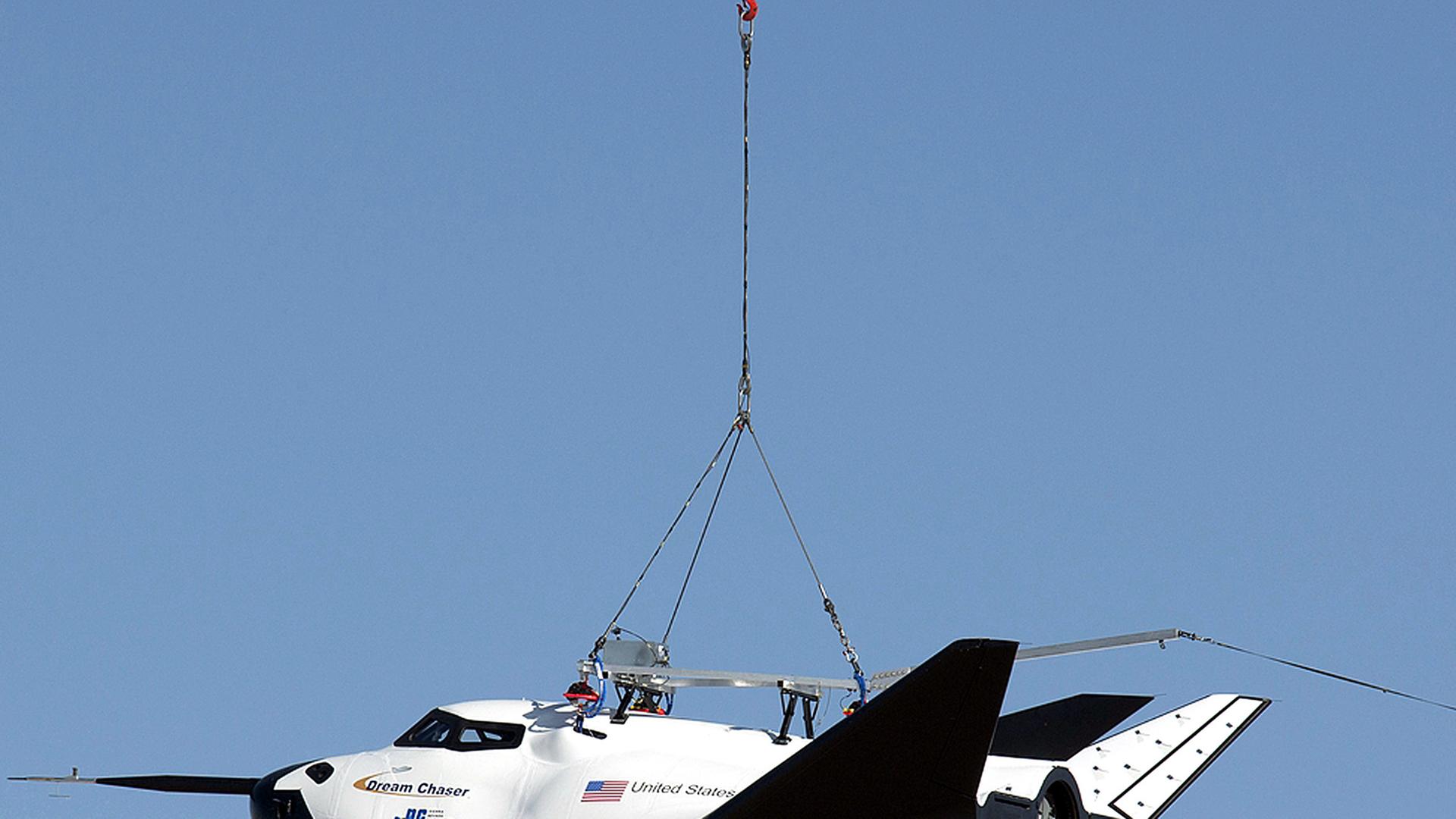 Ein Hubschrauber trägt den Mini-Shuttle Dream Chaser an einem Seil.