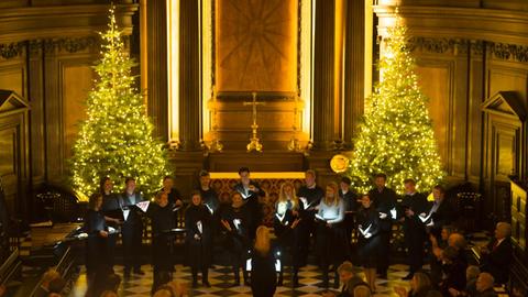 Zwischen zwei beschmückten und leuchtenden Weihnachtsbäumen steht das Ensemble