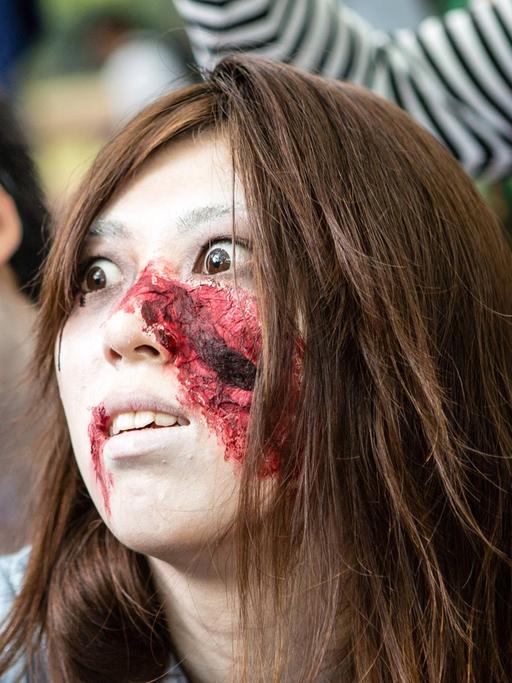 Zu sehen sind als Zombies verkleidete und geschminkte Menschen bei einem Zombie Walk