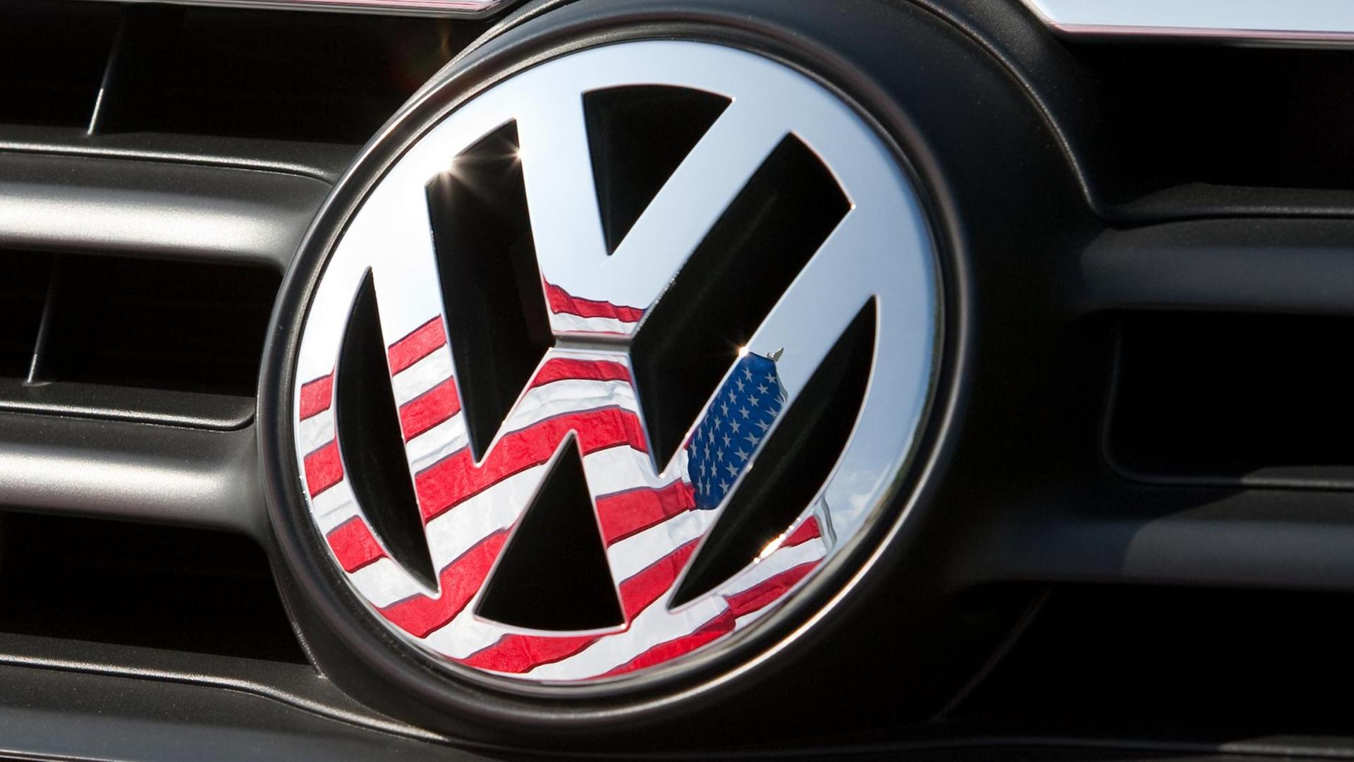 Die US-Flagge spiegelt sich im VW-Zeichen eines Autos.