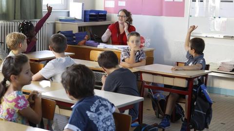 Eine Lehrerin sitzt in Frankreich in einem Klassenzimmer vor ihren Schülern.