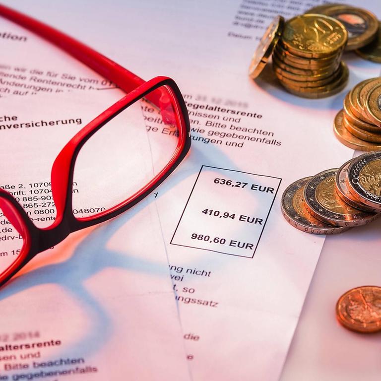 Rentenbescheide liegen auf einem Tisch mit Lesebrille und Kleingeldmünzen, Symbolbild, Ein Rentenbescheid mit Kleingeld Pension decisions lie on a Table with Reading glasses and Symbol image a Pension decision with Small money