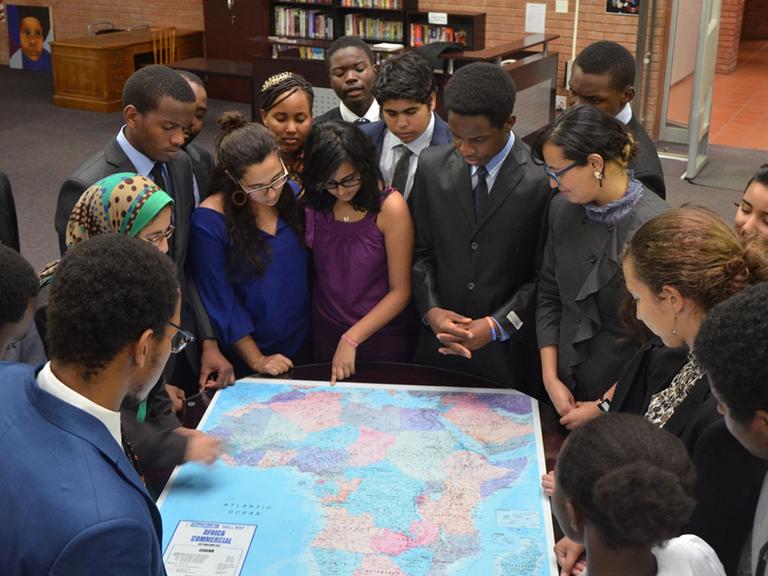 Schülerinnen und Schüler an der African Leadership Academy (ALA) im südafrikanischen Johannesburg stehen um eine Afrikakarte.