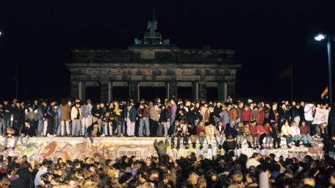 Eine große Menschenmenge versammelte sich am Abend des 10. November 1989 vor und auf der Mauer am Brandenburger Tor in Berlin.