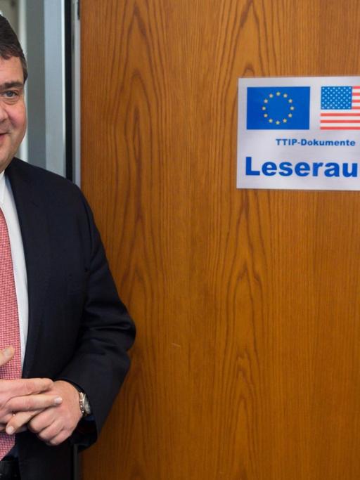 Bundeswirtschaftsminister Sigmar Gabriel (SPD) vor einer Holztür mit der Aufschrift "Leseraum" und der US- und EU-Flagge.