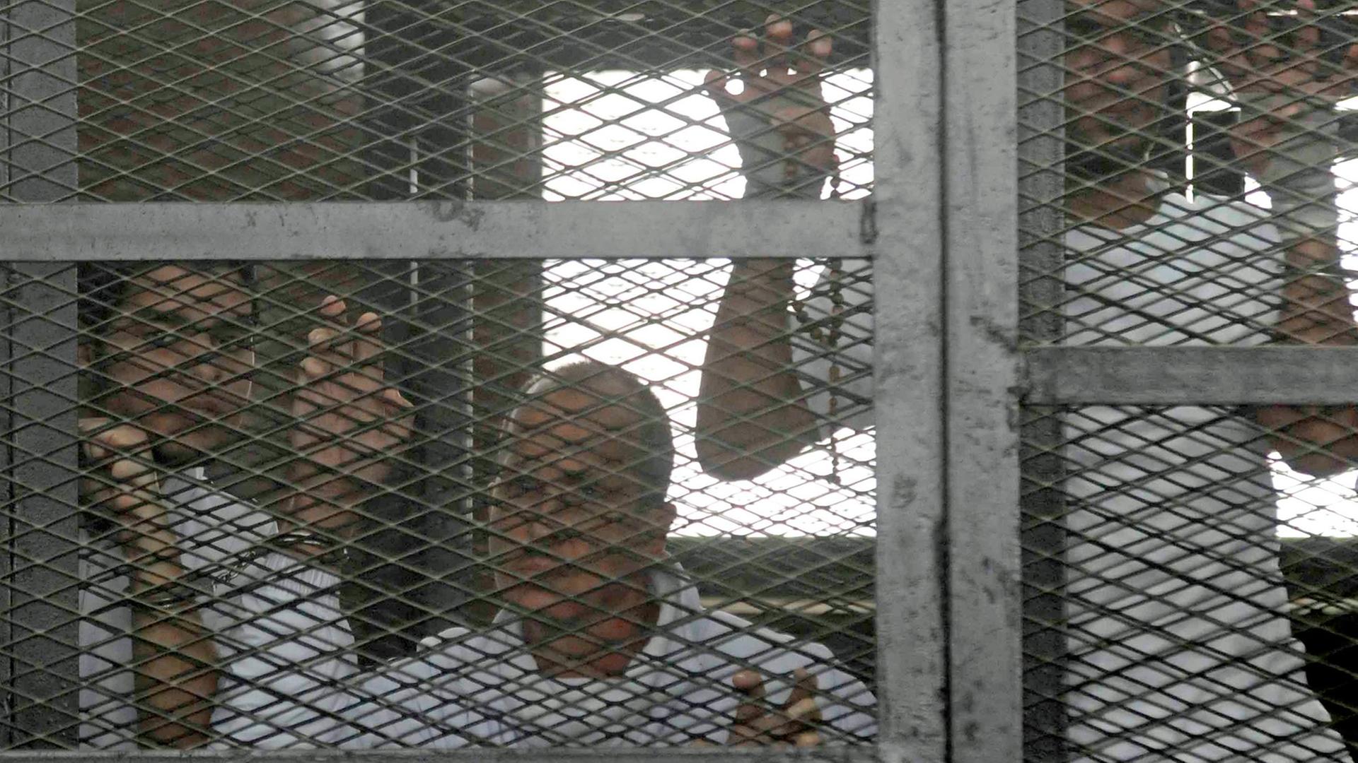 Die verurteilten Journalisten in einem Käfig vor Gericht