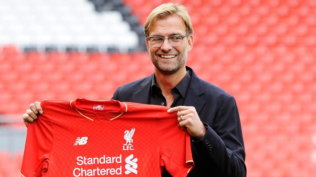 Jürgen Klopp hält ein Trikot des FC Liverpool in die Kamera.