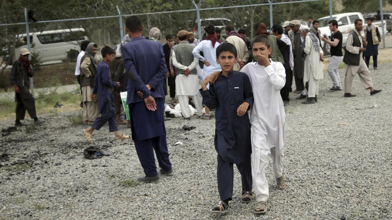 Zwei Jungen gehen in Kabul über einem Platz, auf dem am Nachmittag Bomben explodiert sind.