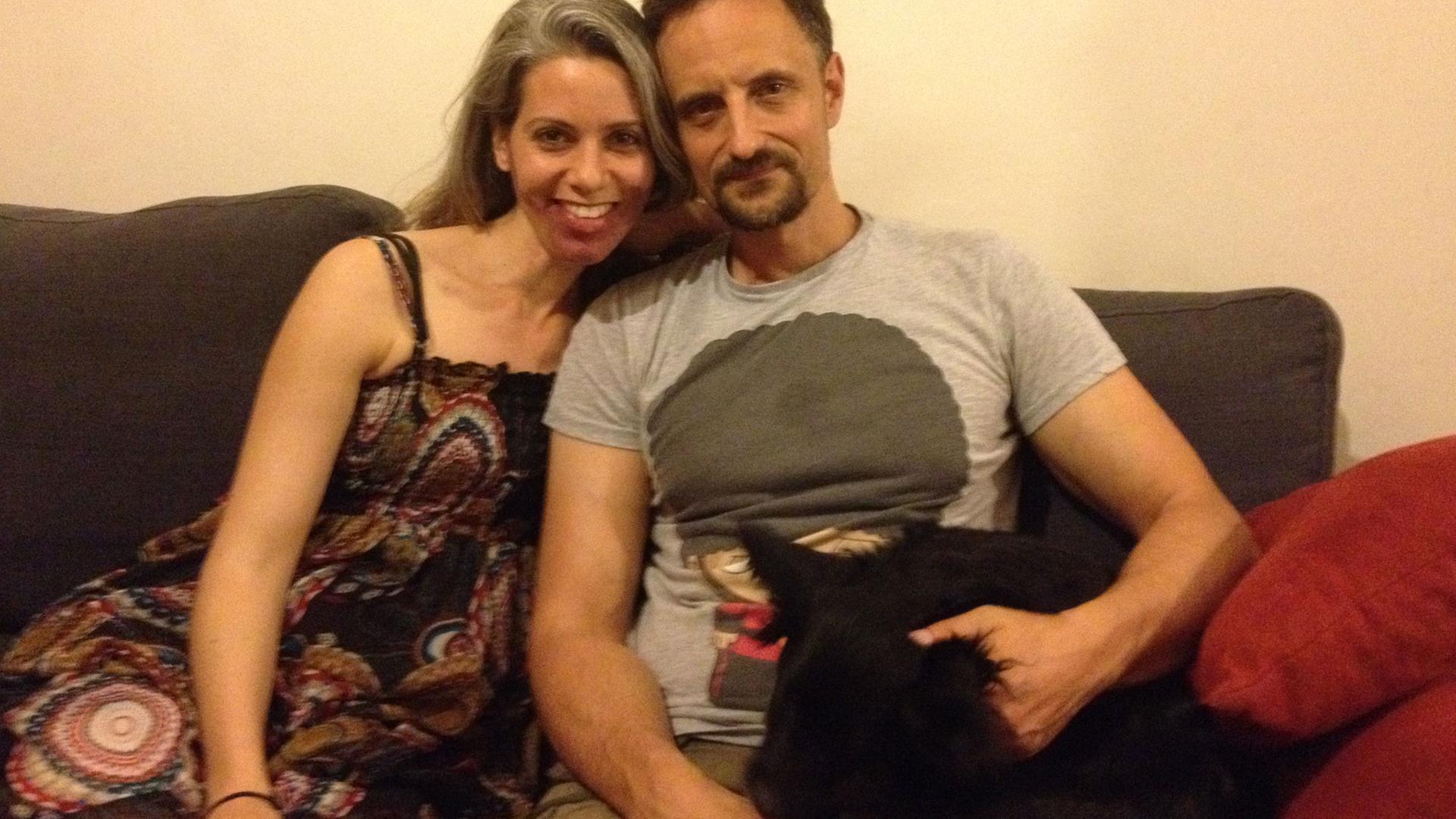 Die 36-jährige Nina und der 42-jährige Sascha auf dem Sofa mit ihrem Hund in ihrer Wohnung in Tel Aviv.