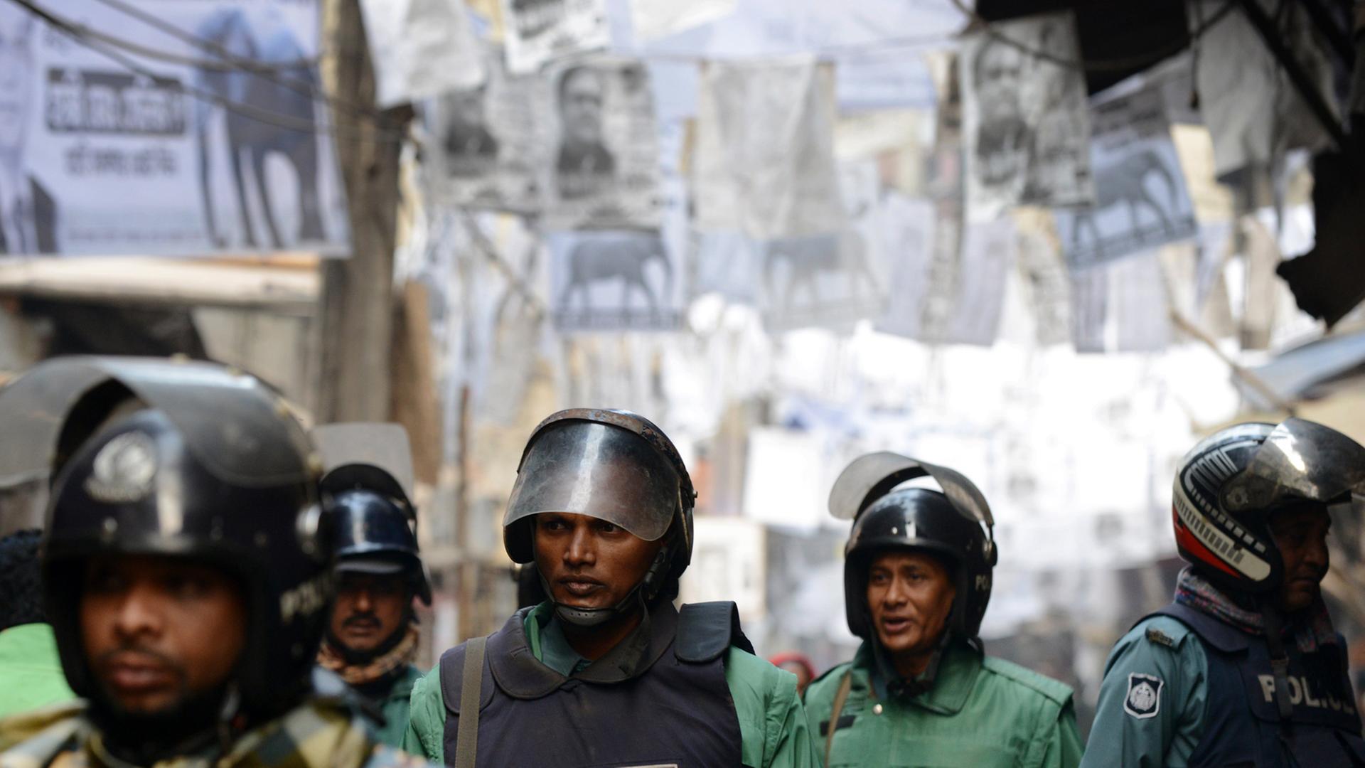 Auf einer Straße in Dhaka stehen fünf Polizisten mit Helmen und Schutzwesten.