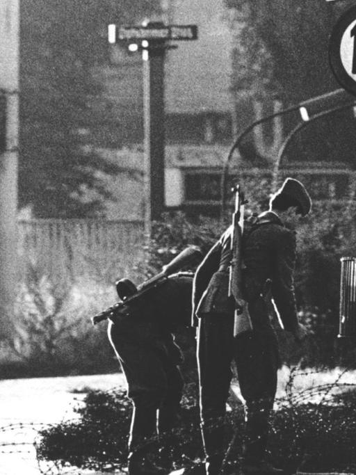 Volkspolizisten beim Errichten von Stacheldrahtsperren am Potsdamer Platz. Am frühen Sonntagmorgen des 13. August 1961 wurde unter der Aufsicht von bewaffneten Streitkräften der DDR mit der Errichtung von Straßensperren aus Stacheldraht und dem Bau einer Mauer begonnen, um den Ostteil Berlins vom Westteil abzusperren. Die Mauer soll den ständig steigenden Flüchtlingsstrom von Ost- nach West-Berlin stoppen.