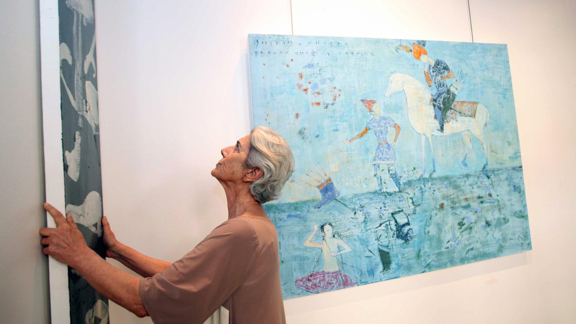 Blick in die Ausstellung von Reza Derakshani in der Dar al-Funoon Art Gallery in Kuwait City im Juni 2012 – Kuratorin Lucia Topalian hängt die Bilder; aktuell ist der Künstler in Chemnitz zu sehen.