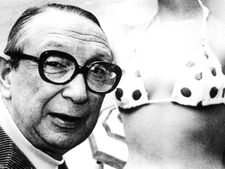 Ein Schwarz-Weiß-Foto zeigt Louis Reard im Jahr 1974 neben einer Modepuppe, die einen gepunkteten Bikini trägt.