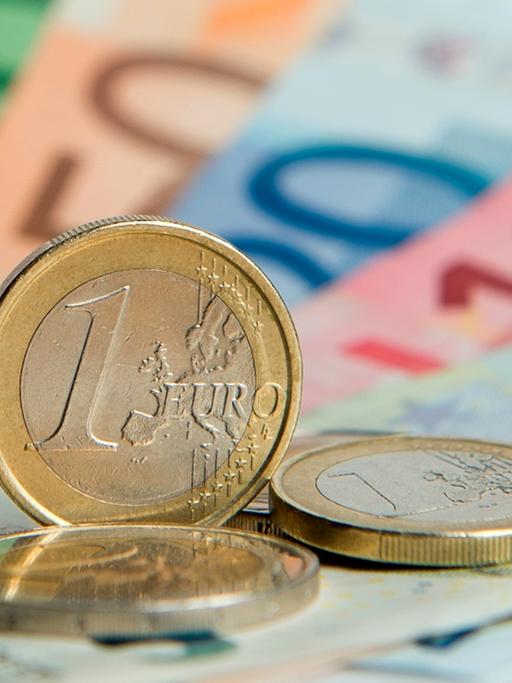 Euroscheine und Euromünzen liegen auf einem Tisch. 