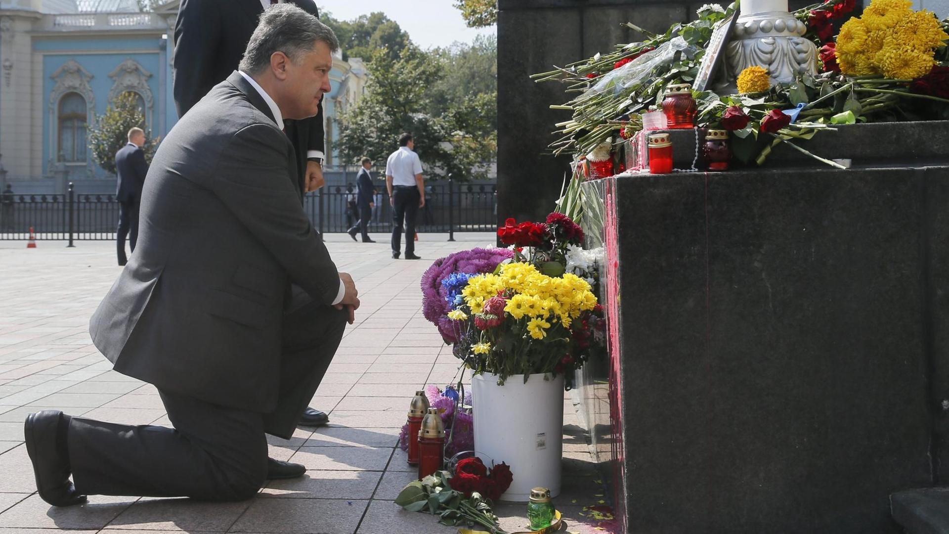 Der ukrainische Präsident Poroschenko kniet vor einer Gedenknische für die Opfer der gewaltsamen Ausschreitungen vor dem Parlament in Kiew nieder.