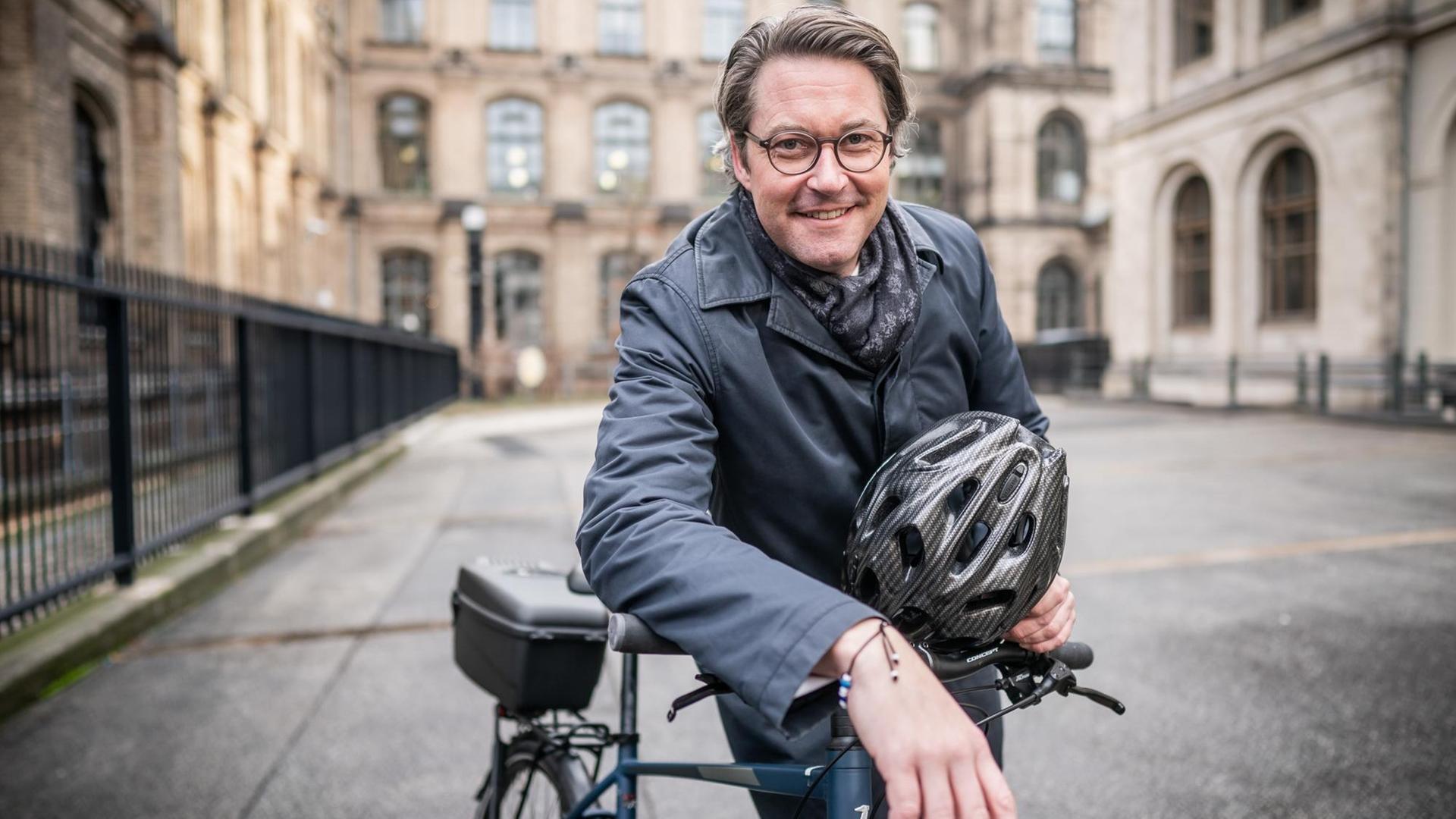 Andreas Scheuer (CSU), Bundesminister für Verkehr und digitale Infrastruktur, lehnt sich am 17.12.2019 im Innenhof des Ministeriums auf ein Fahrrad, einen Helm in der Hand.
