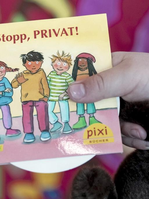 Ein Kind hält in einer Kita in Berlin bei dessen Vorstellung das neue Pixi-Buch mit dem Titel "Stopp, PRIVAT!"