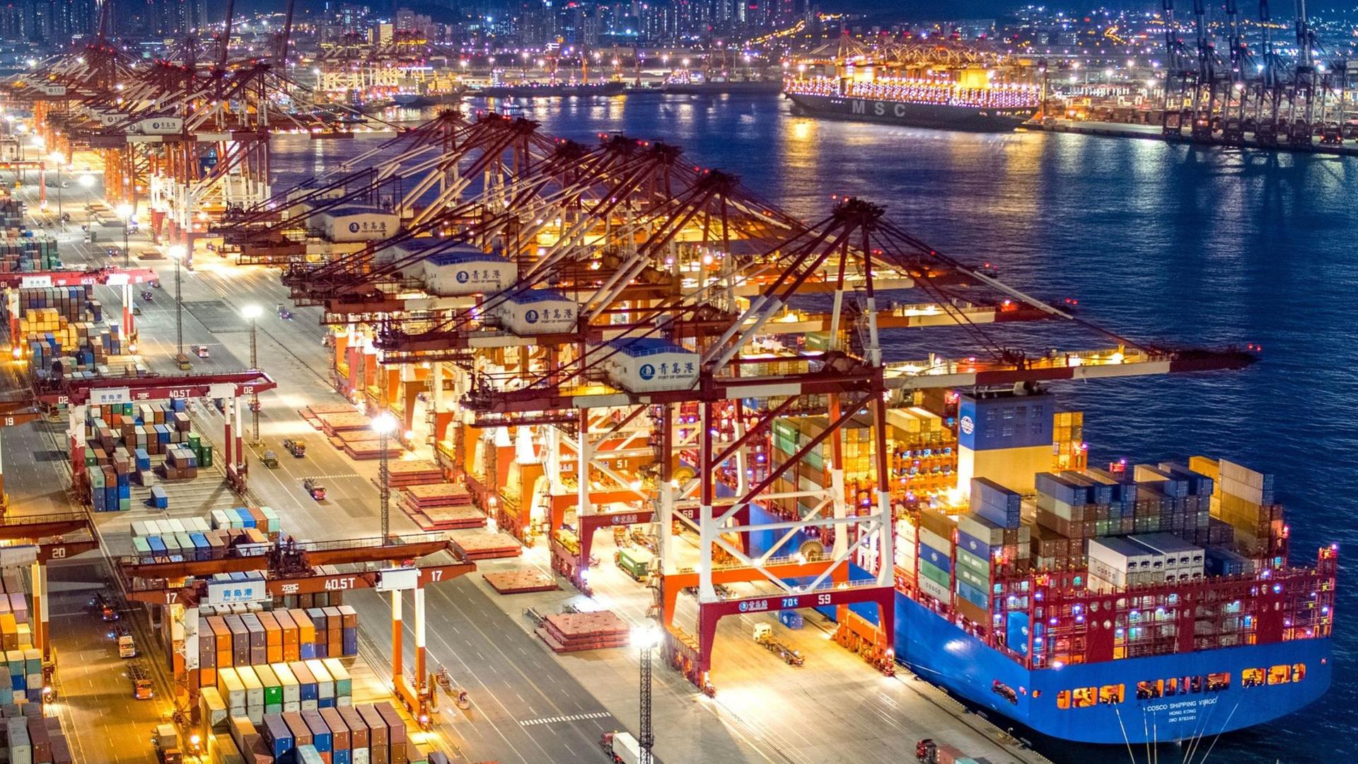 China, Qingdao: Containerschiffe liegen am nächtlich beleuchteten Containerterminal des Hafens von Qingdao.
