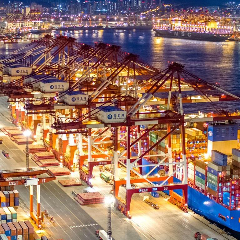 China, Qingdao: Containerschiffe liegen am nächtlich beleuchteten Containerterminal des Hafens von Qingdao.