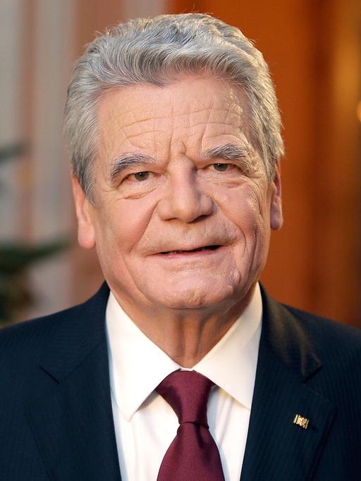 Bundespräsident Gauck nach seiner Weihnachtsansprache, im Hintergrund ein geschmückter Weihnachtsbaum und die deutsche Flagge.