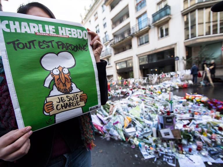 Eine Frau zeigt die erste Ausgabe des Satiremagazins "Charlie Hebdo" nach den Anschlägen von Paris.