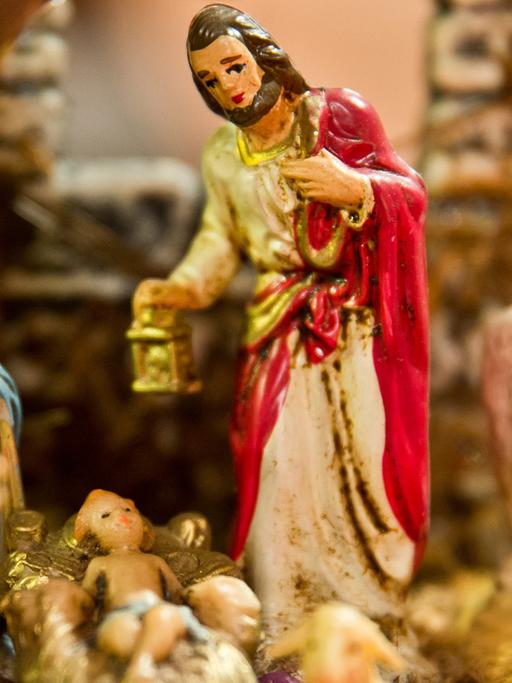 Josef mit Maria und dem Jesuskind als Figuren in einer Weihnachtskrippe